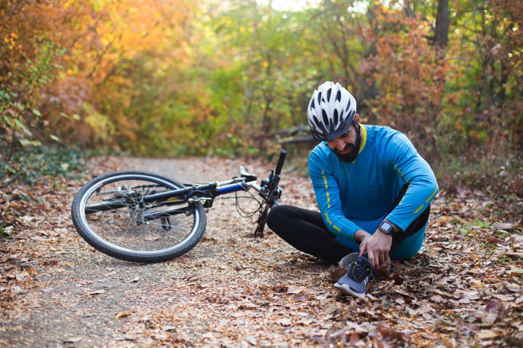 Cyclist holding ankle next to bicycle